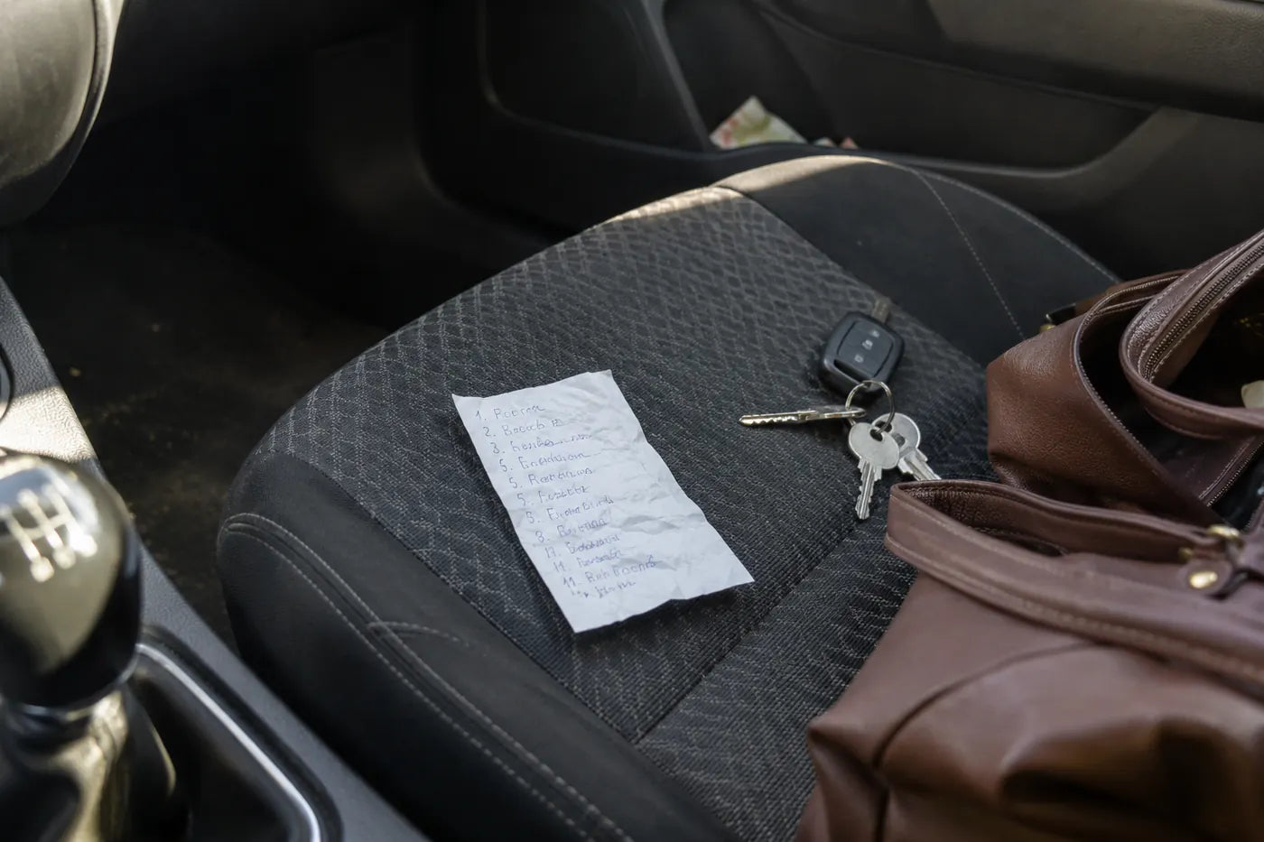 Un bon mototolit cu notițe scrise cu pixul, pe scaunul pasagerului, lângă chei și geantă