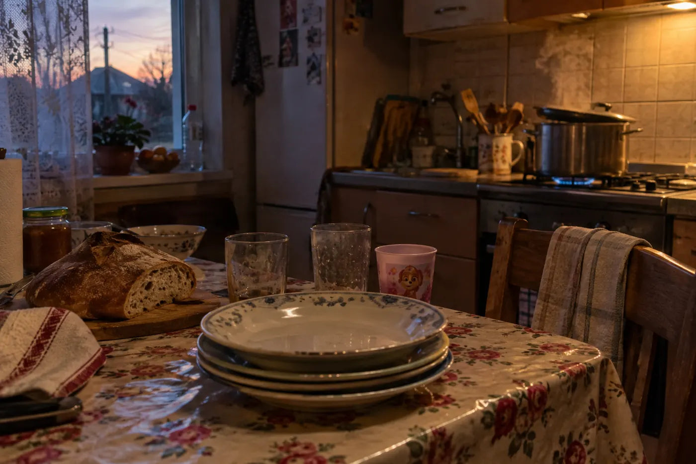 O oală pe aragaz și farfurii puse pentru toată familia, pe o masă de bucătărie